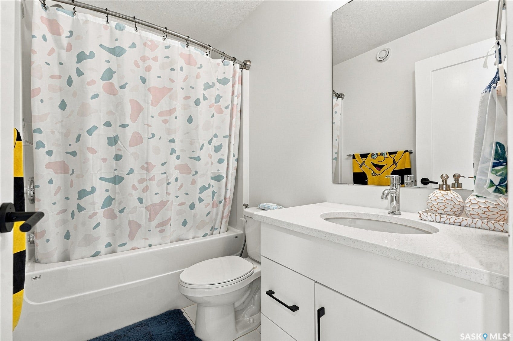 White vanity with a light-colored countertop, undermount sink, and black hardware