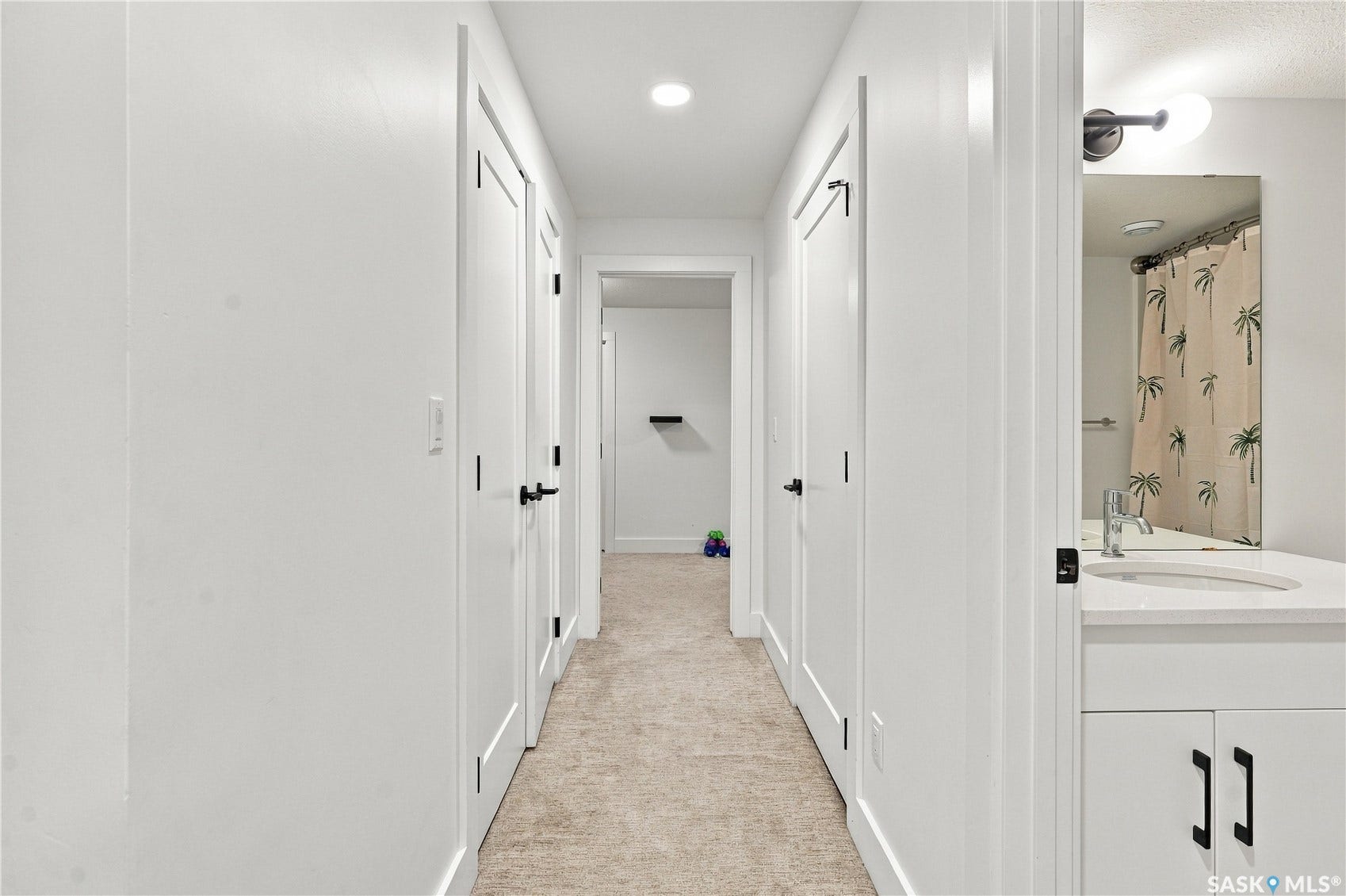 Hallway featuring neutral carpet, recessed lighting, and multiple doors with black hardware