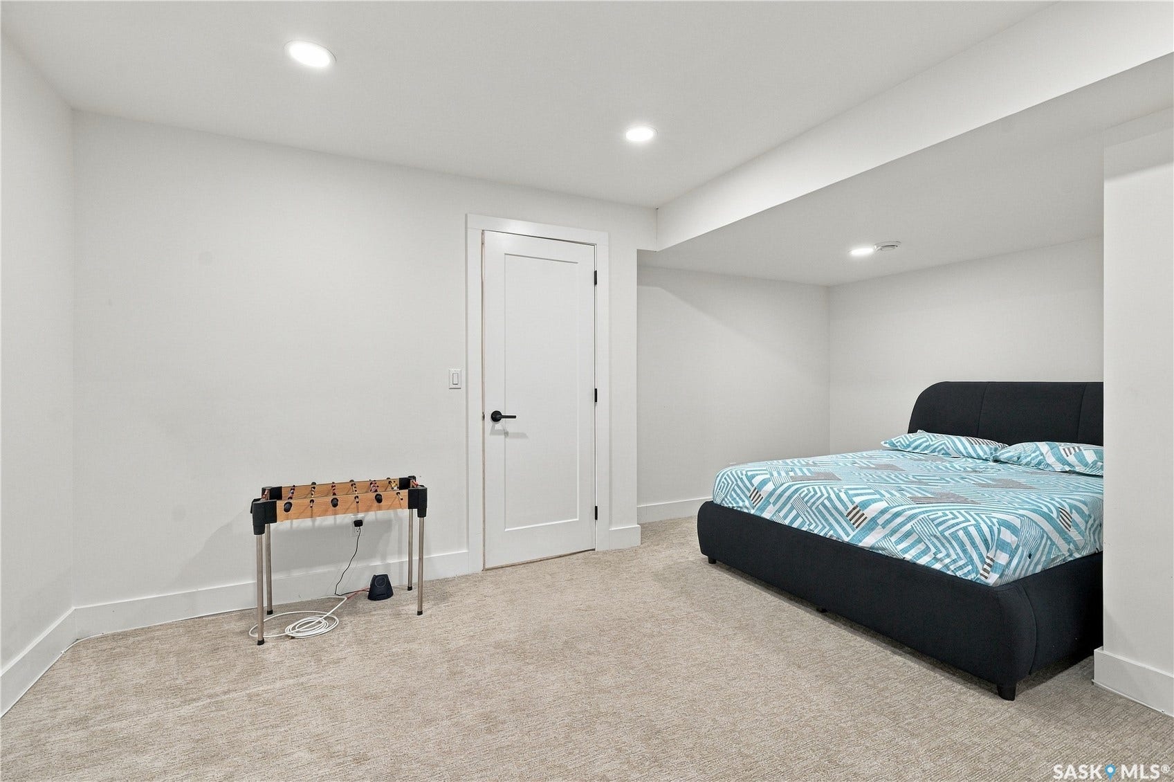 Recessed lighting illuminates the space, featuring light-toned carpeting and a white door with black hardware
