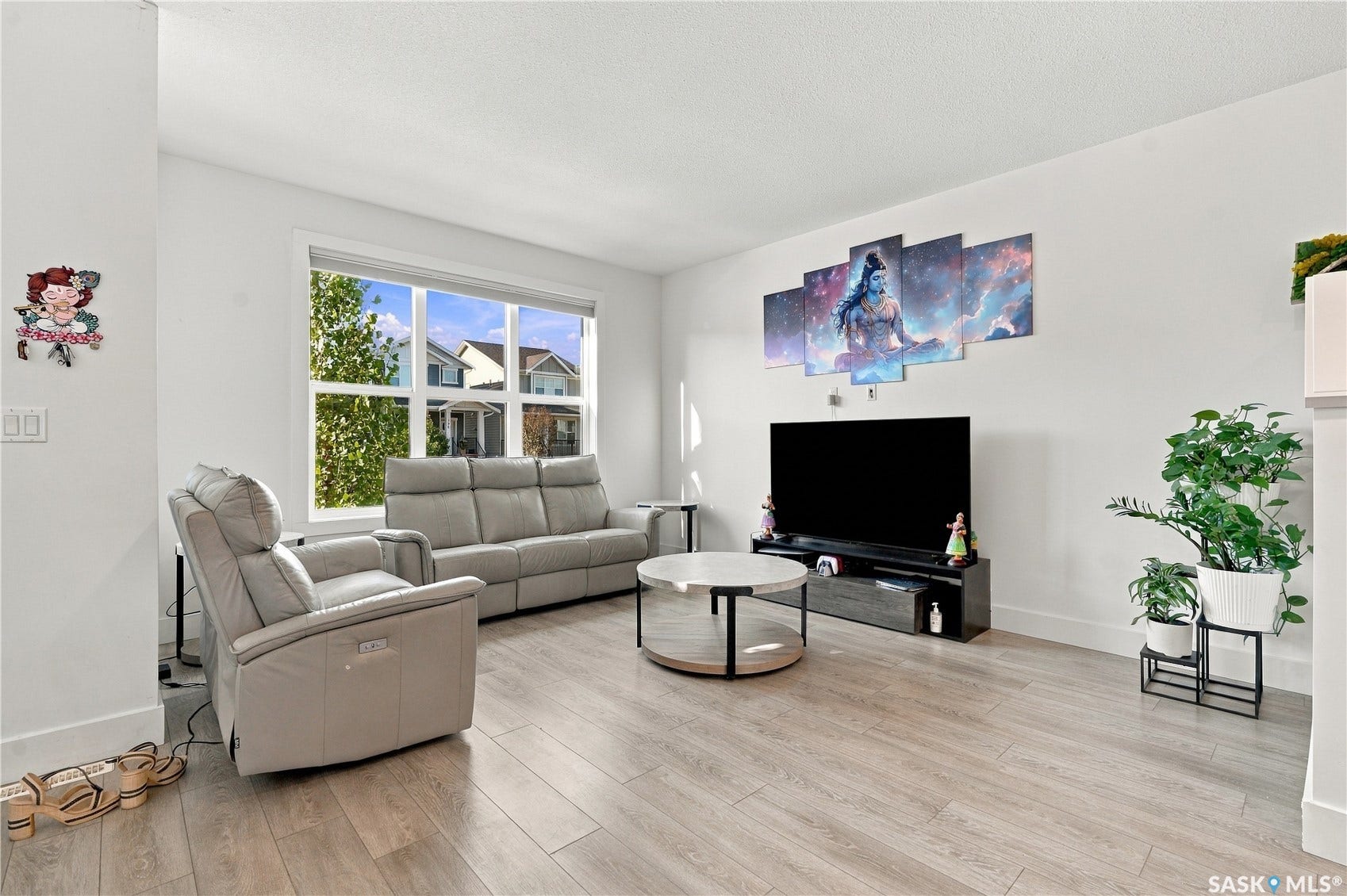 Light wood-finish flooring, white walls, and a large window with white trim