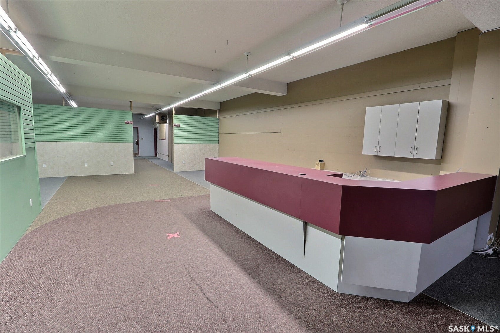 Built-in reception desk, overhead cabinetry, partial wall partitions, and carpet flooring