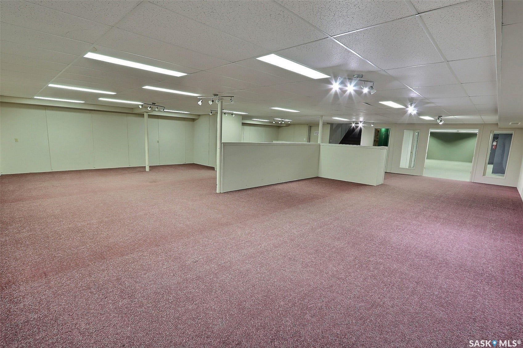Expansive carpeted area with drop ceiling, recessed lighting, track lighting, and partition walls