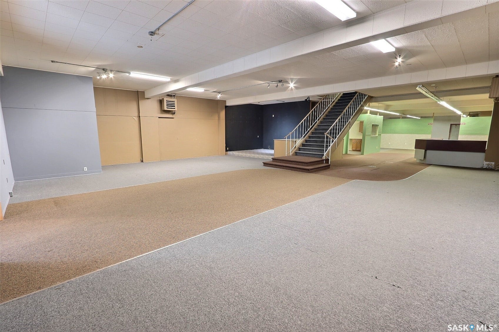 Multi-level open-concept space featuring staircase, track lighting, and a built-in counter