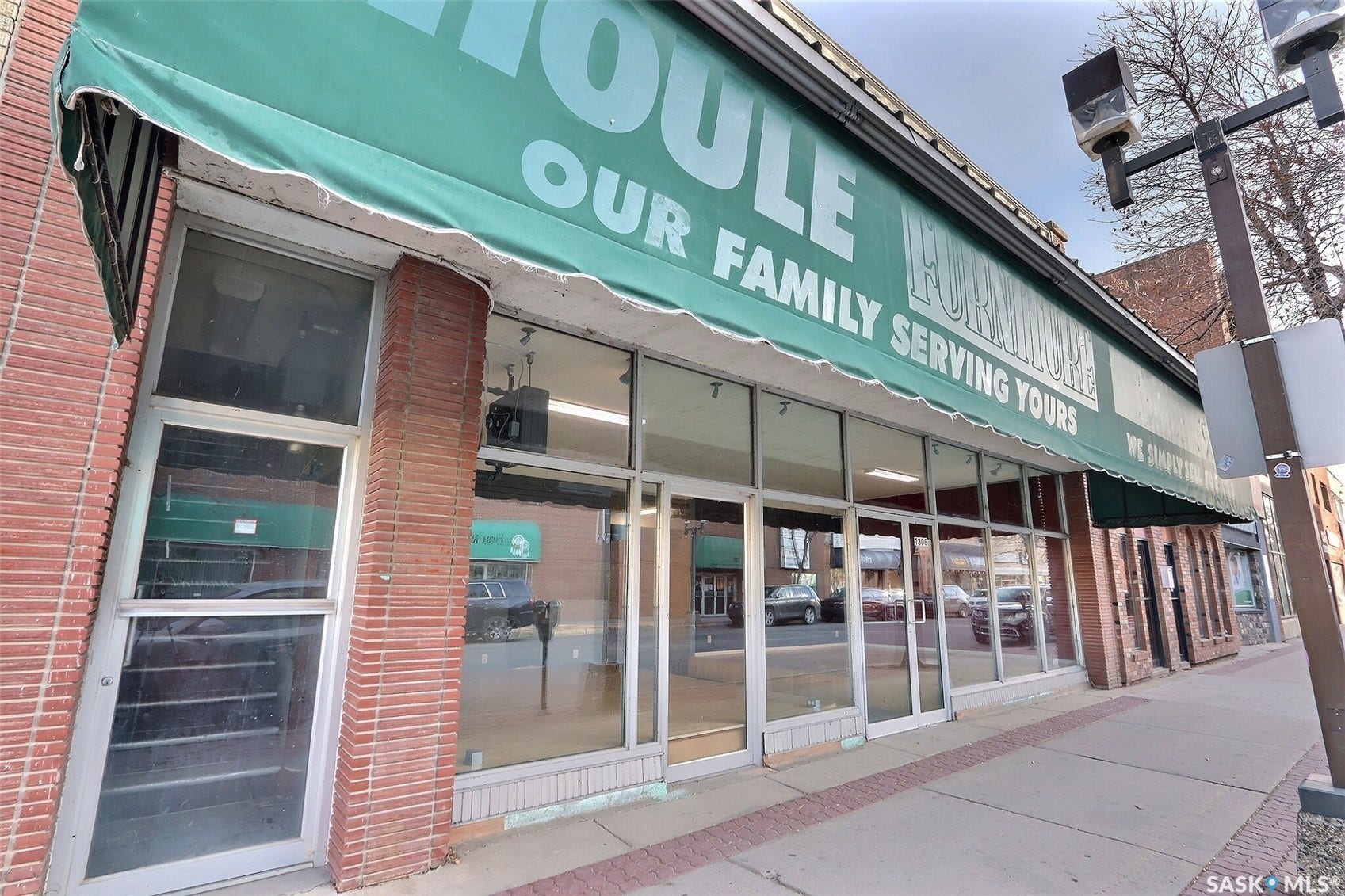 Commercial storefront featuring a green awning, extensive window frontage, and red brick accents