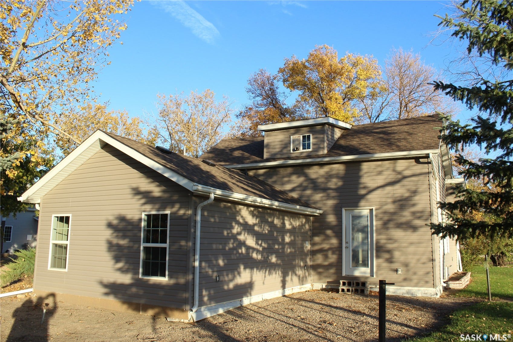Brown siding exterior with white trim, a dormer window, and a gabled roof