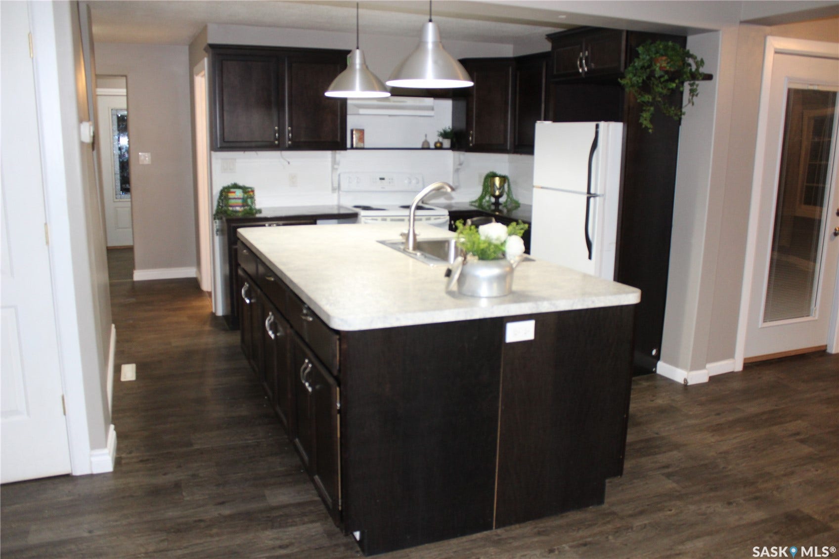 Kitchen featuring dark wood-finish cabinetry, light-toned countertops, and wood-finish flooring