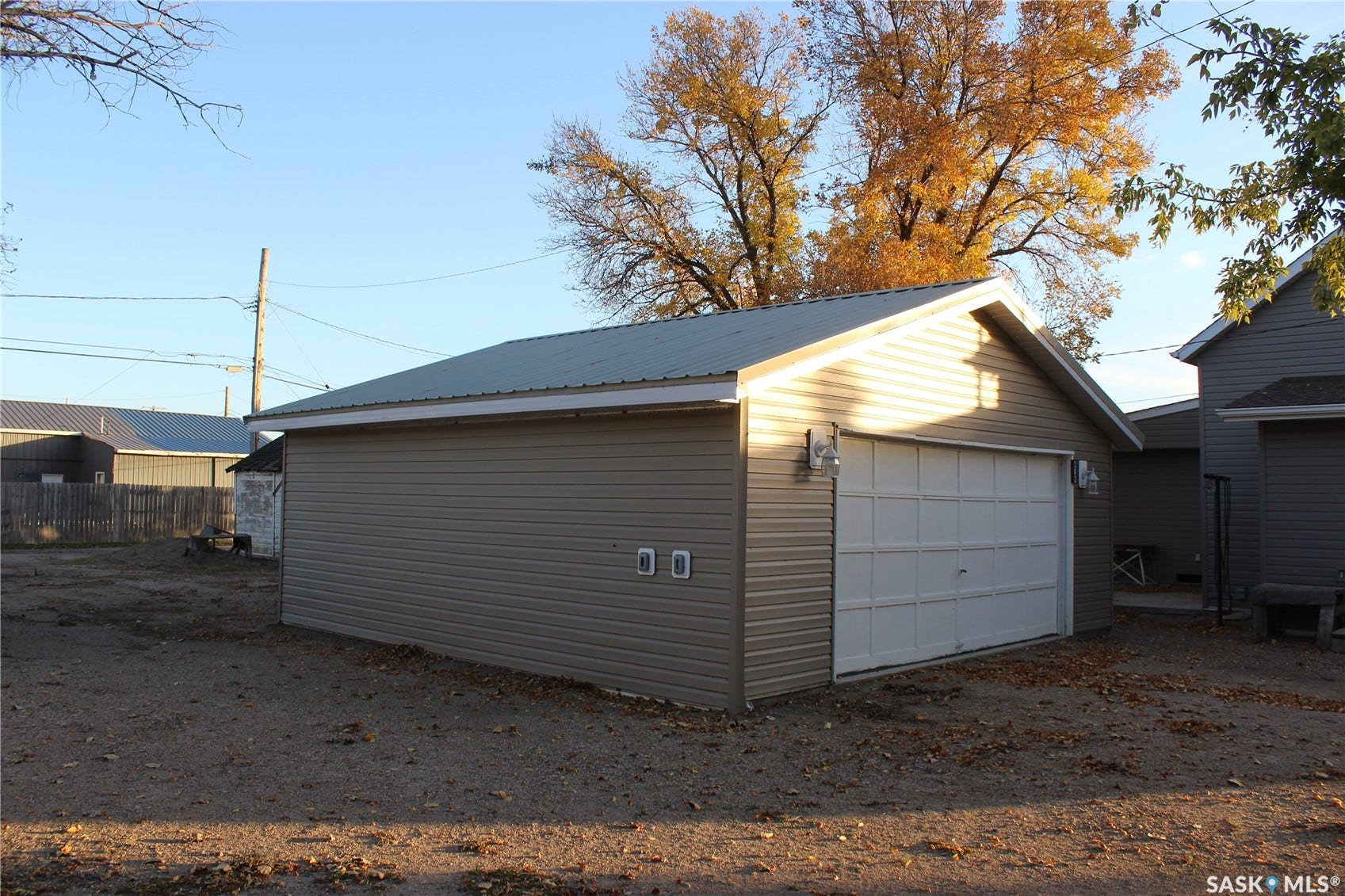 Detached garage with horizontal siding, a metal roof, and a panel-style garage door