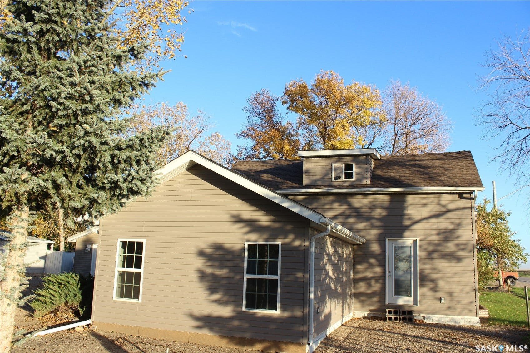 Tan vinyl siding exterior with white window trim