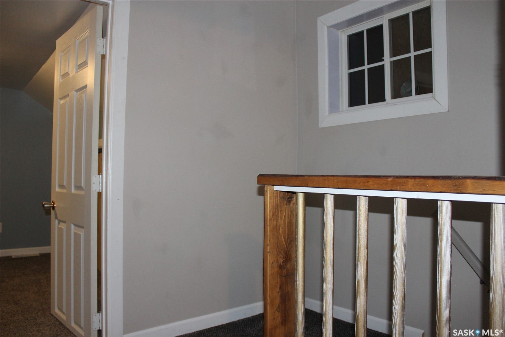 Interior architectural features include a four-panel door, a window with grid inserts, and a wood-finish handrail with vertical balusters