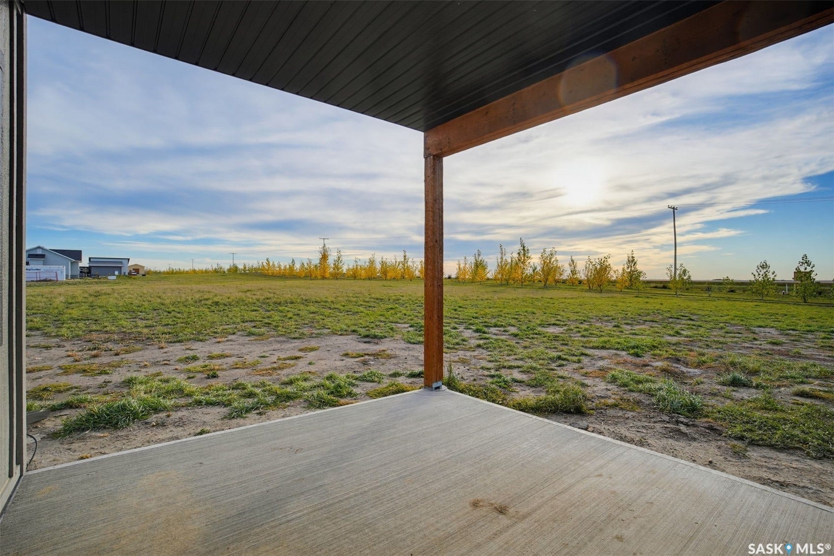 Concrete patio with a wood-finish support beam and an expansive grass area