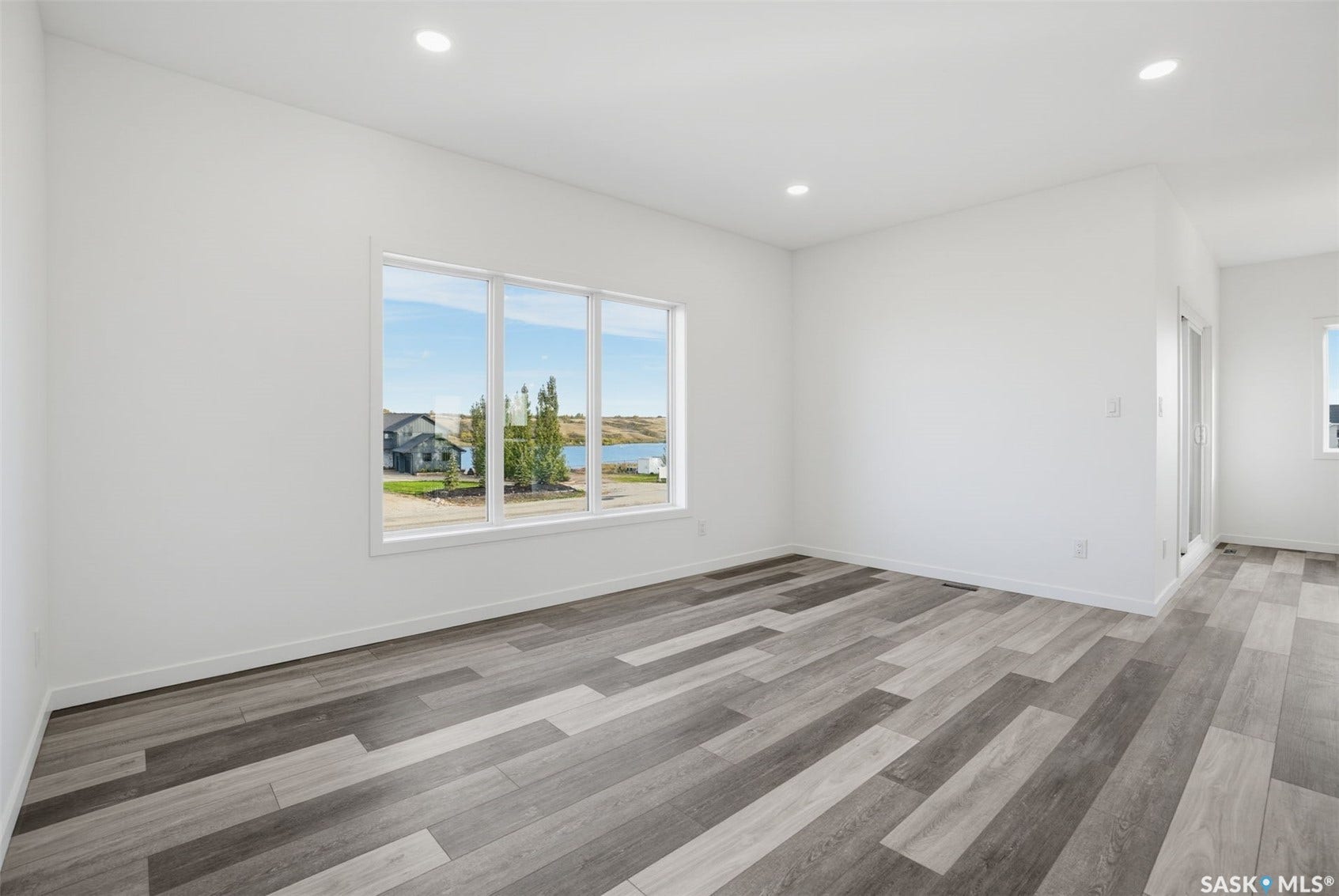 Recessed lighting, wood-finish flooring, white walls, multiple large windows, and a sliding glass door