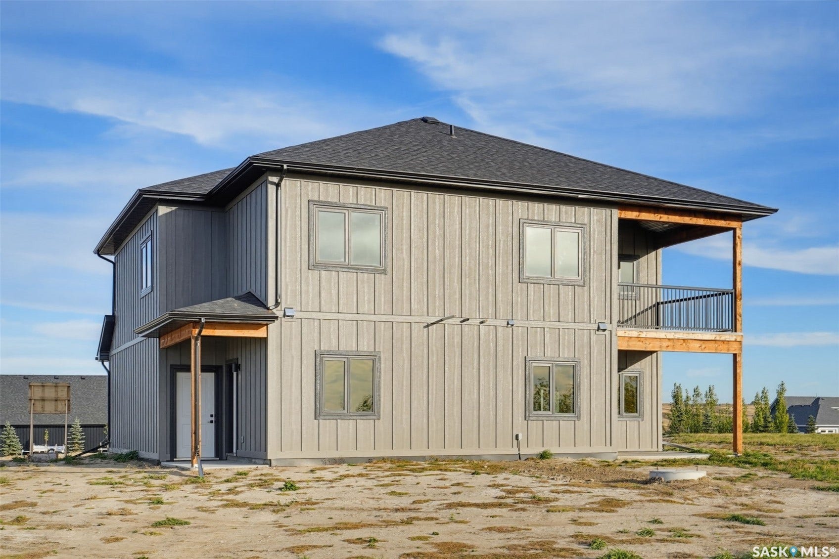 Two-story exterior with board and batten style siding, charcoal shingle roof, covered entry, and upper-level covered deck with black railing