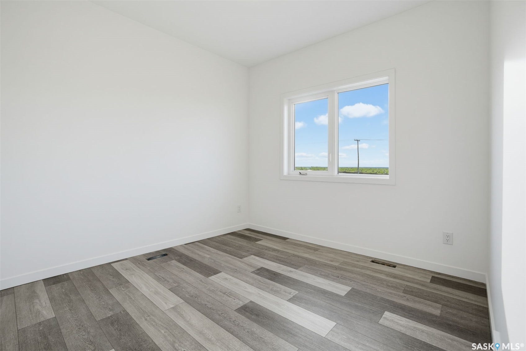 Neutral white walls, wood-finish flooring, and a double-pane window
