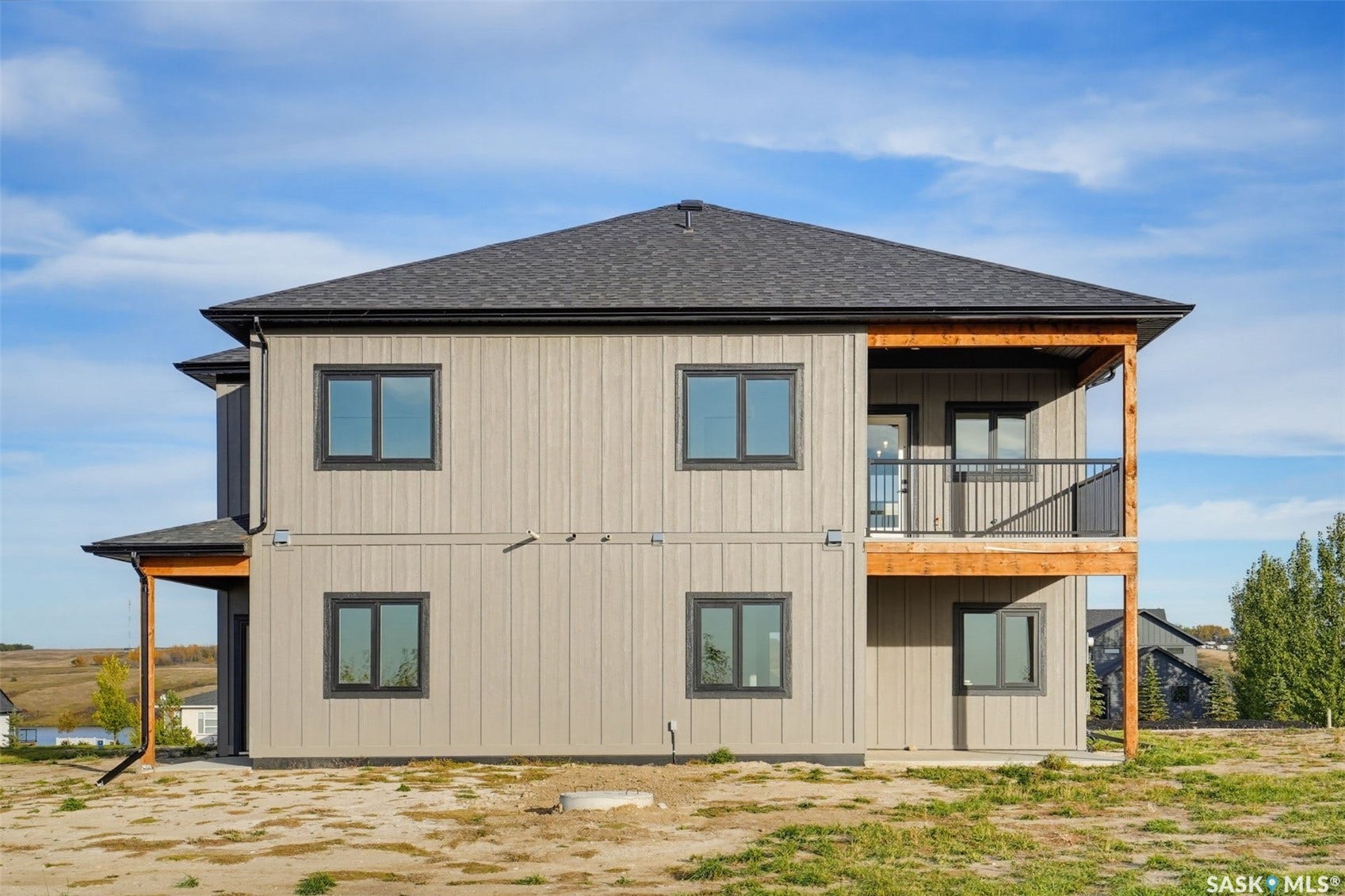 Two-story exterior with board and batten style siding, dark-framed windows, and an upper-level balcony featuring black railings and wood-tone supports
