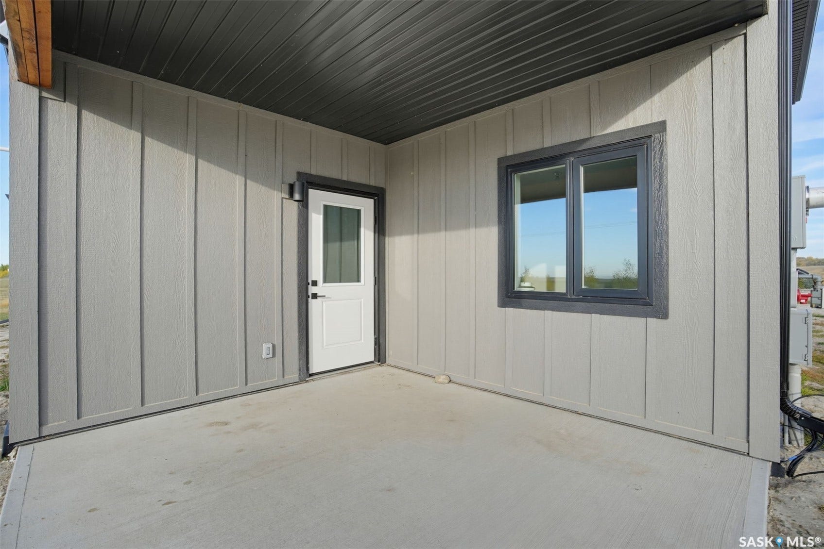 Covered concrete patio with vertical plank siding and dark trim