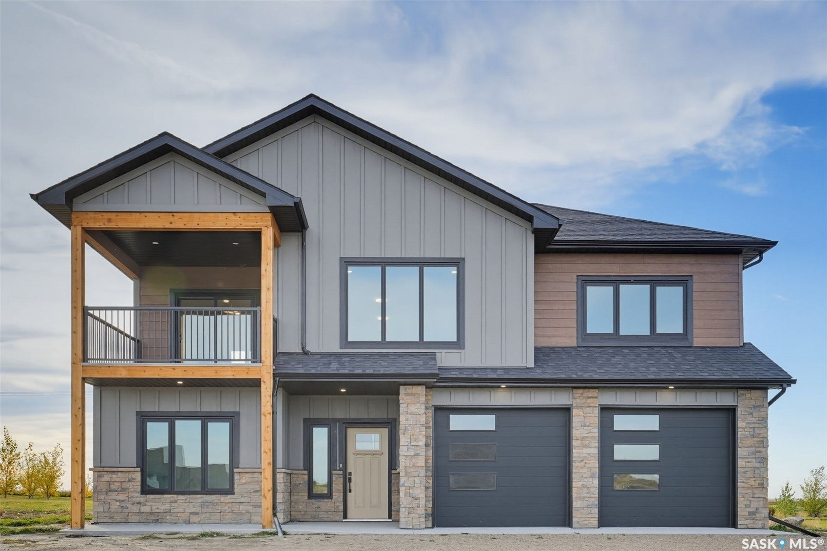 Contemporary exterior featuring vertical siding, stone accents, a multi-pane entry door, and two garage doors with frosted glass panels