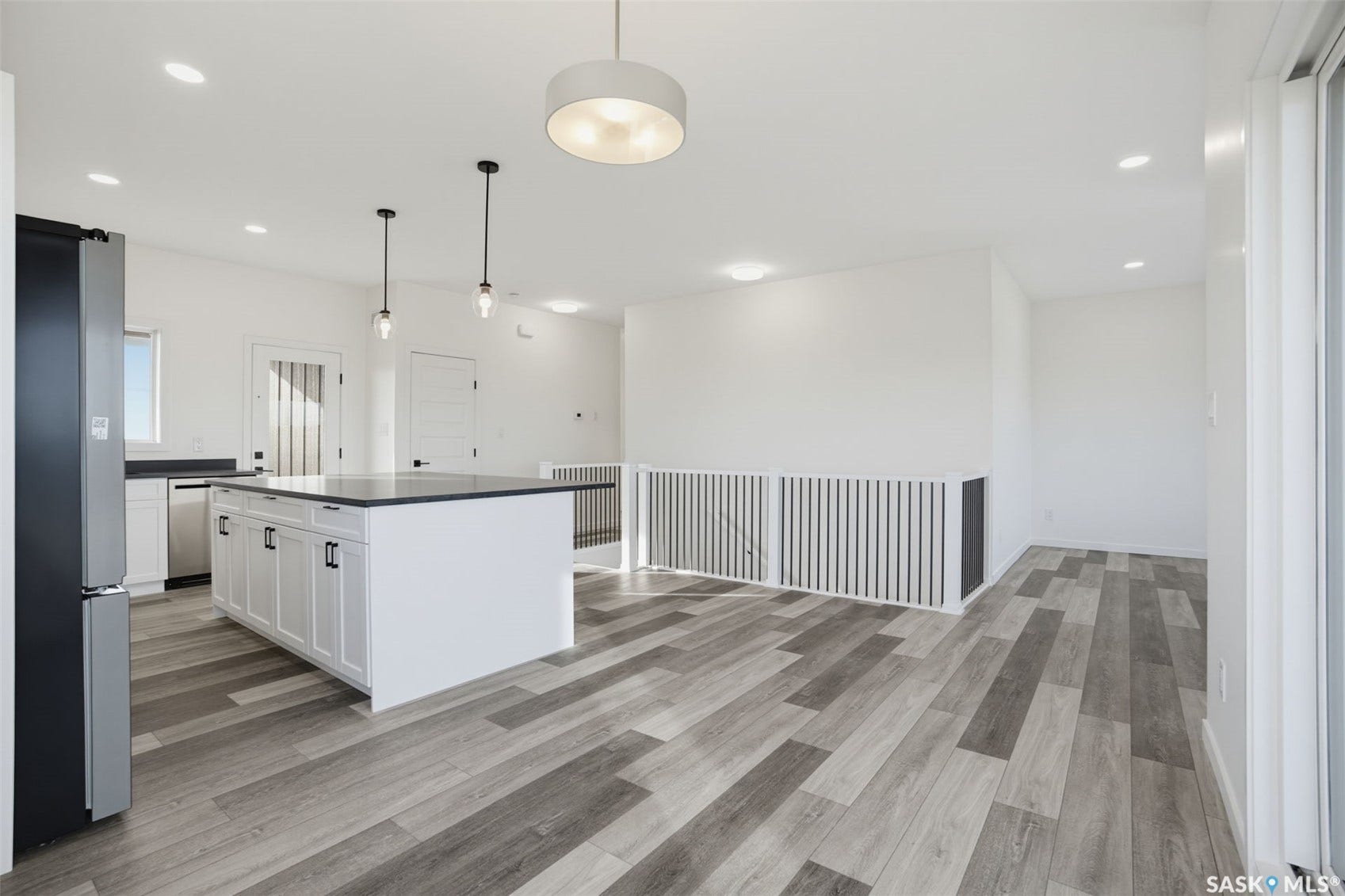 Open concept living space featuring wood-finish flooring, recessed lighting, and a white kitchen island with dark countertops