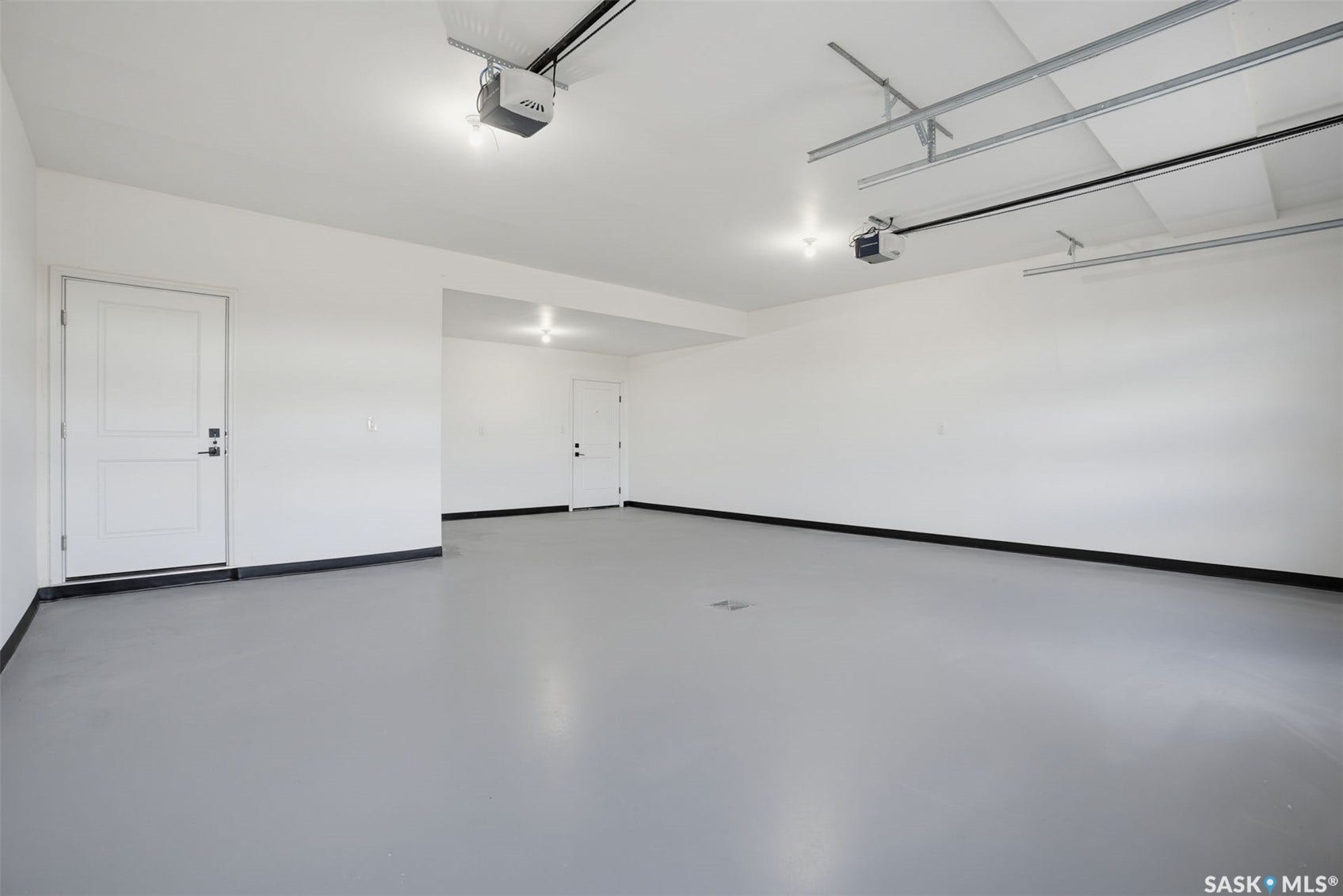 Spacious garage featuring a light gray floor, white walls, and two internal access doors