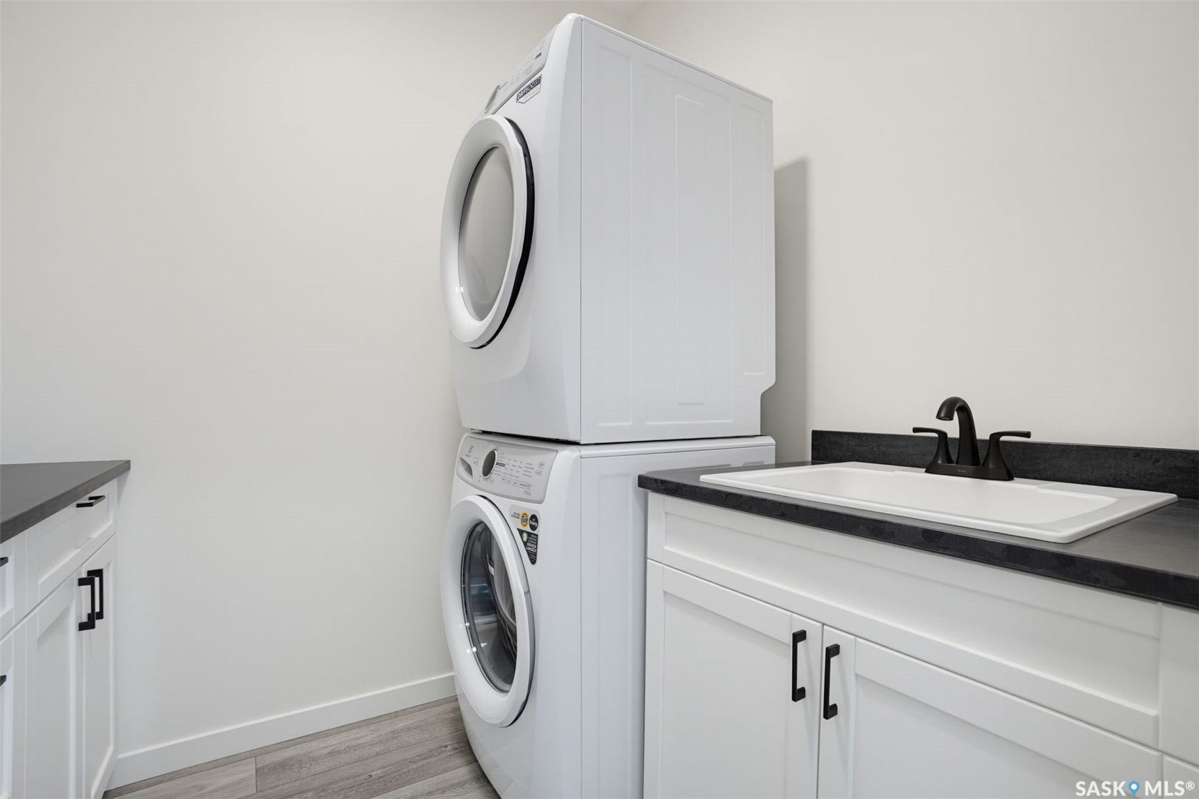 White cabinetry, dark countertops, and a white sink with a matte black faucet