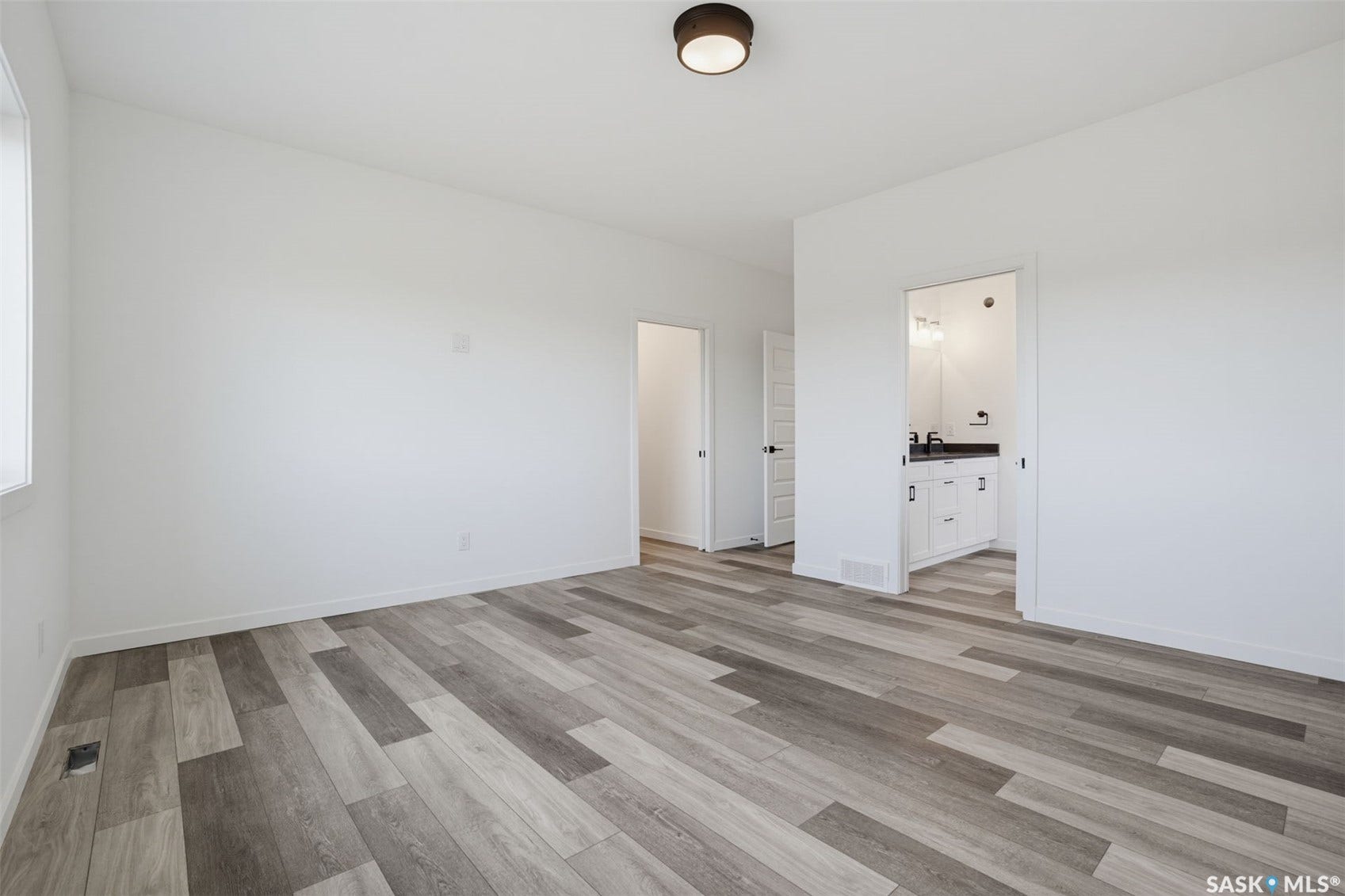 Wood-finish flooring, white walls, and a contemporary flush-mount ceiling light
