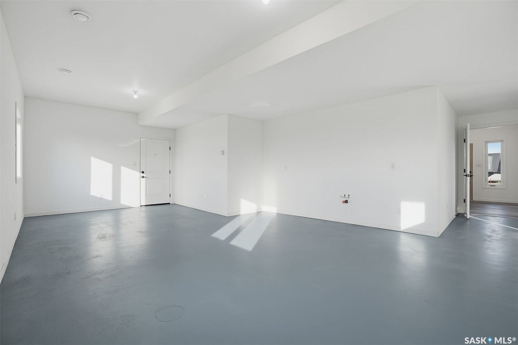 Expansive open area with light gray finished flooring, white walls, and a recessed ceiling light