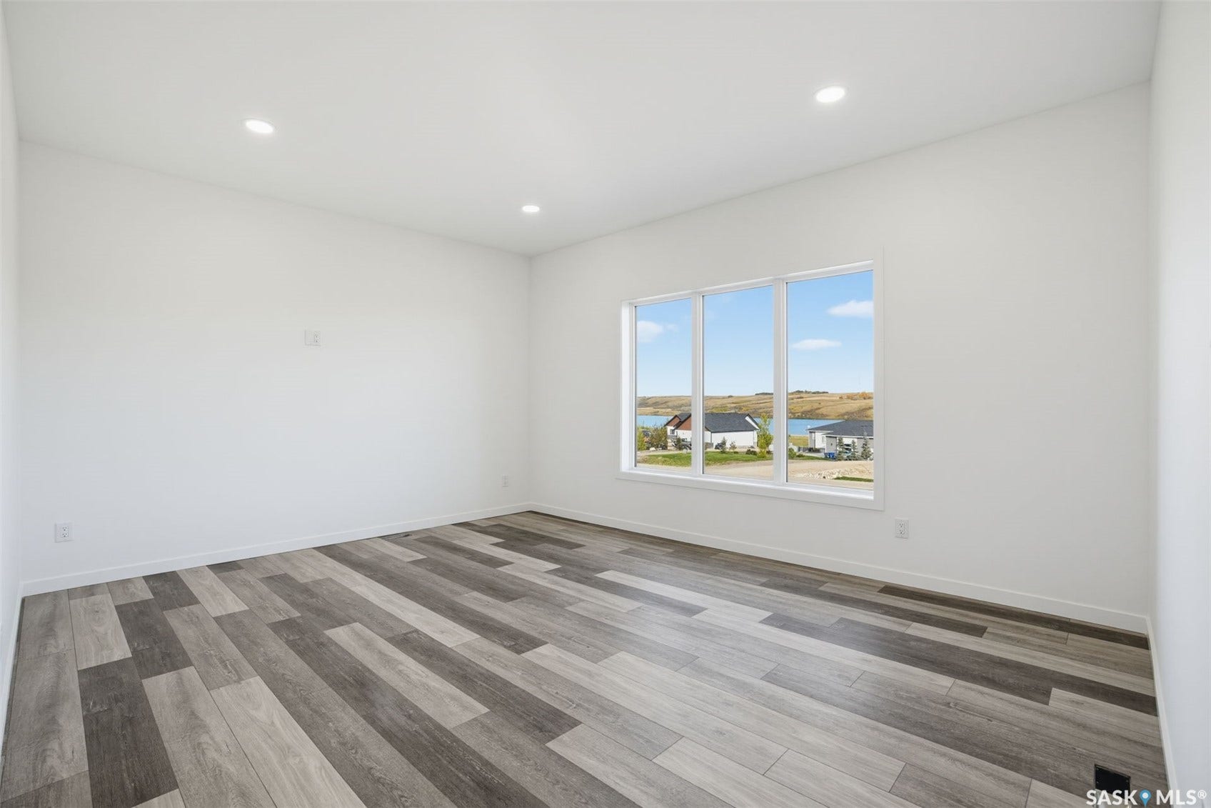 Recessed lighting, wood-finish flooring, white walls, and a multi-pane window