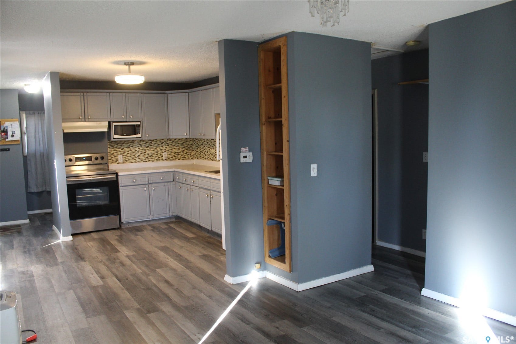 513 2nd Street W, Wilkie SK S0K 4W0 Wood-finish flooring, built-in shelving, updated kitchen cabinetry, stainless steel appliances, and a tiled backsplash