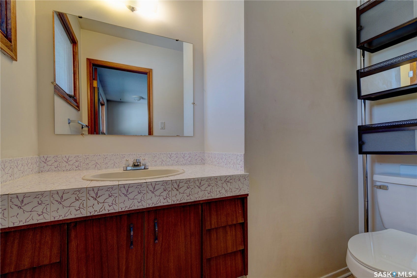Vanity with wood-finish cabinetry, integrated sink, and patterned countertop