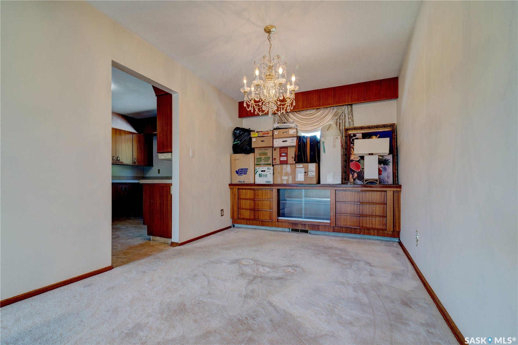 Ceiling-mounted chandelier, built-in wooden cabinetry with glass-front display, and wall-to-wall carpeting