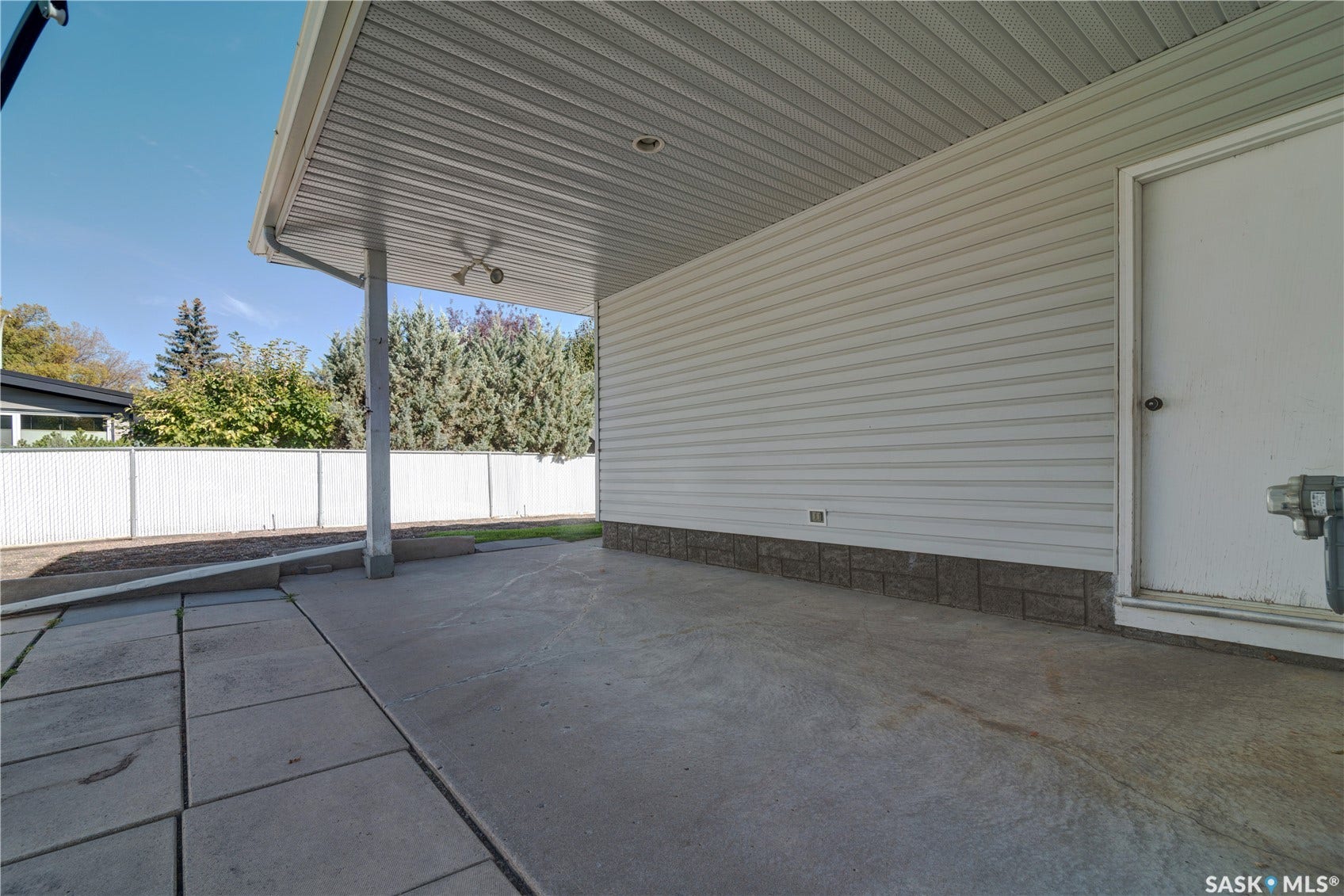 Covered patio with durable vinyl siding, stone veneer foundation, and exterior lighting
