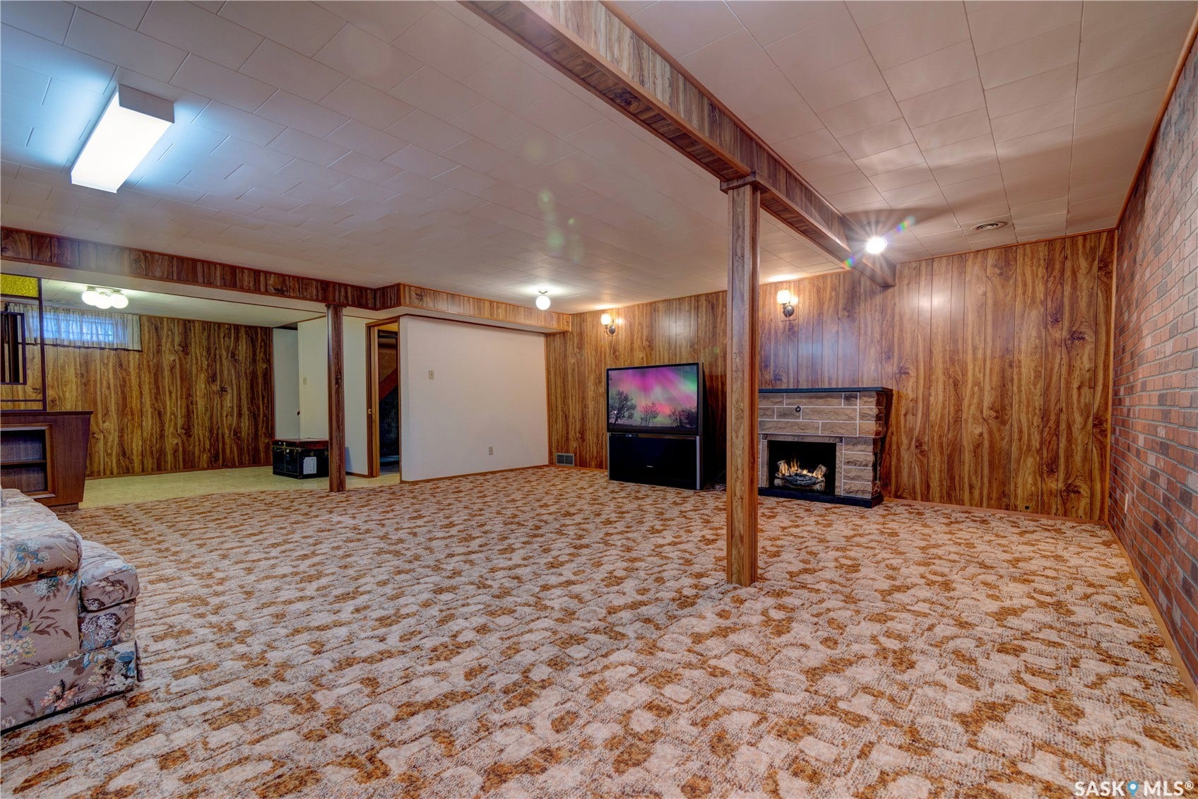 Finished basement space featuring wood-finish wall panels and a brick accent wall