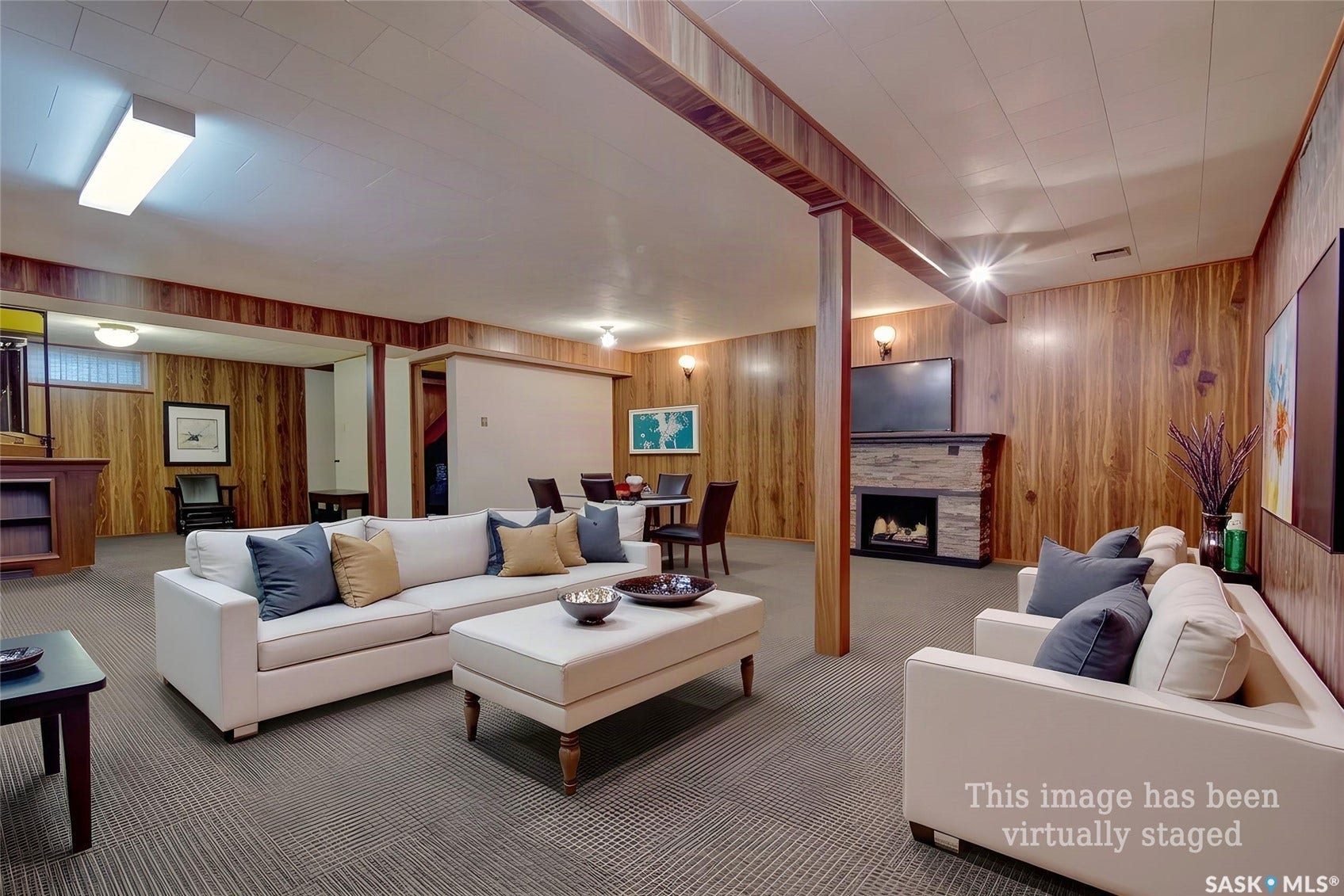 Wood-paneled walls with coordinating structural beams, fireplace with stone surround, and recessed lighting