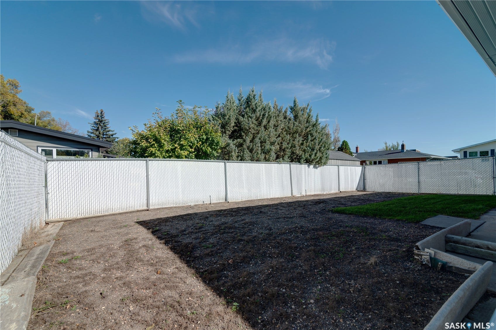 Fenced backyard featuring a partial lawn area and exposed earth