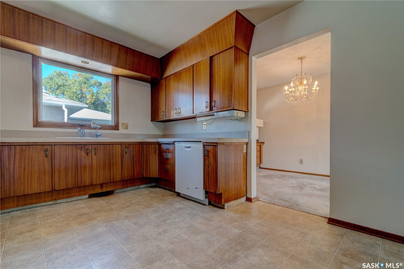 Wood-finish cabinetry and countertops with a built-in sink and white dishwasher