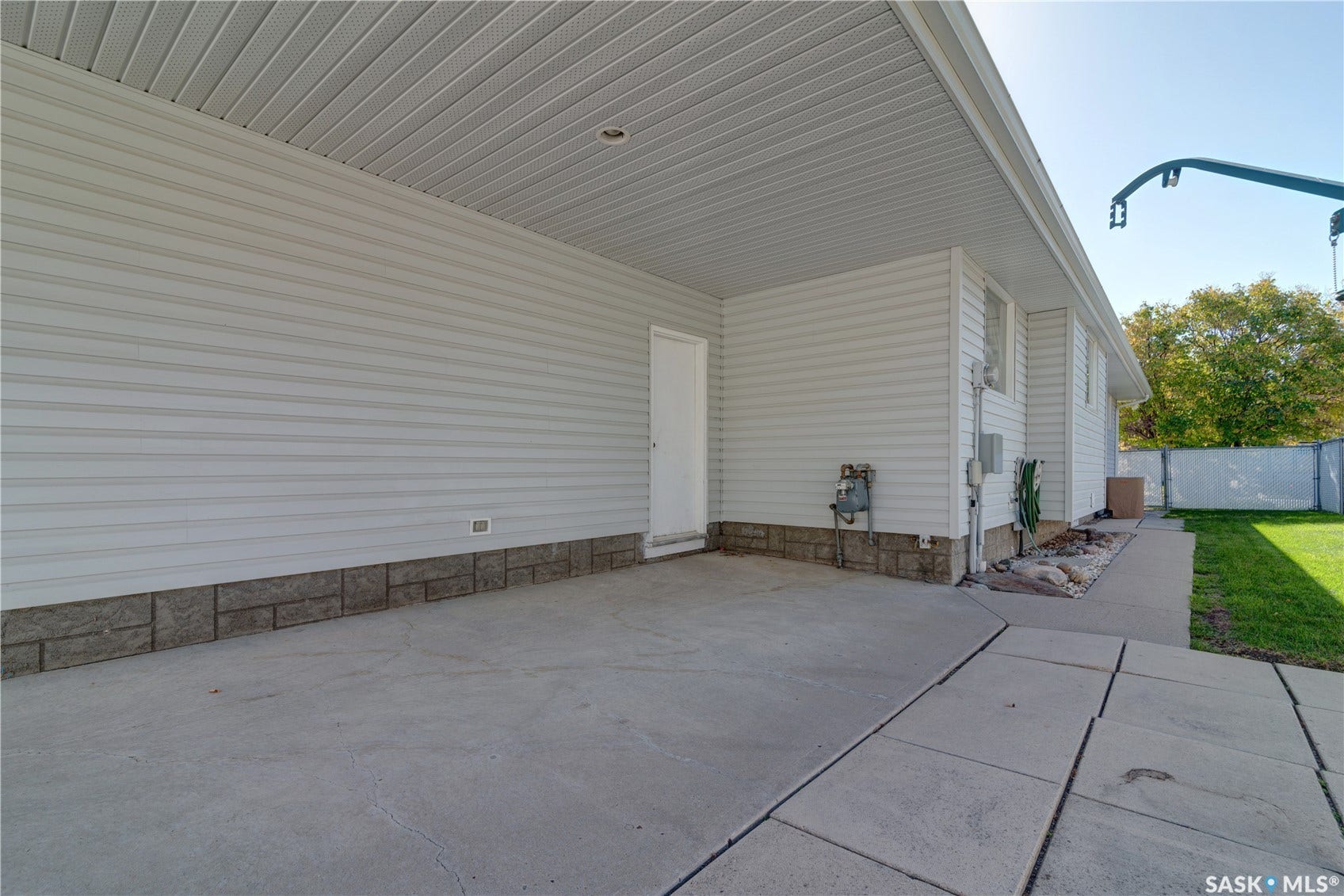 Covered concrete patio with white vinyl siding and stone veneer detailing