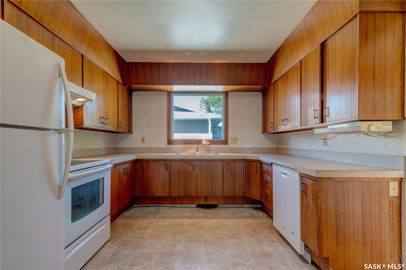 Kitchen featuring wood-finish cabinetry, U-shaped countertops, stainless steel sink, and window with exterior exposure