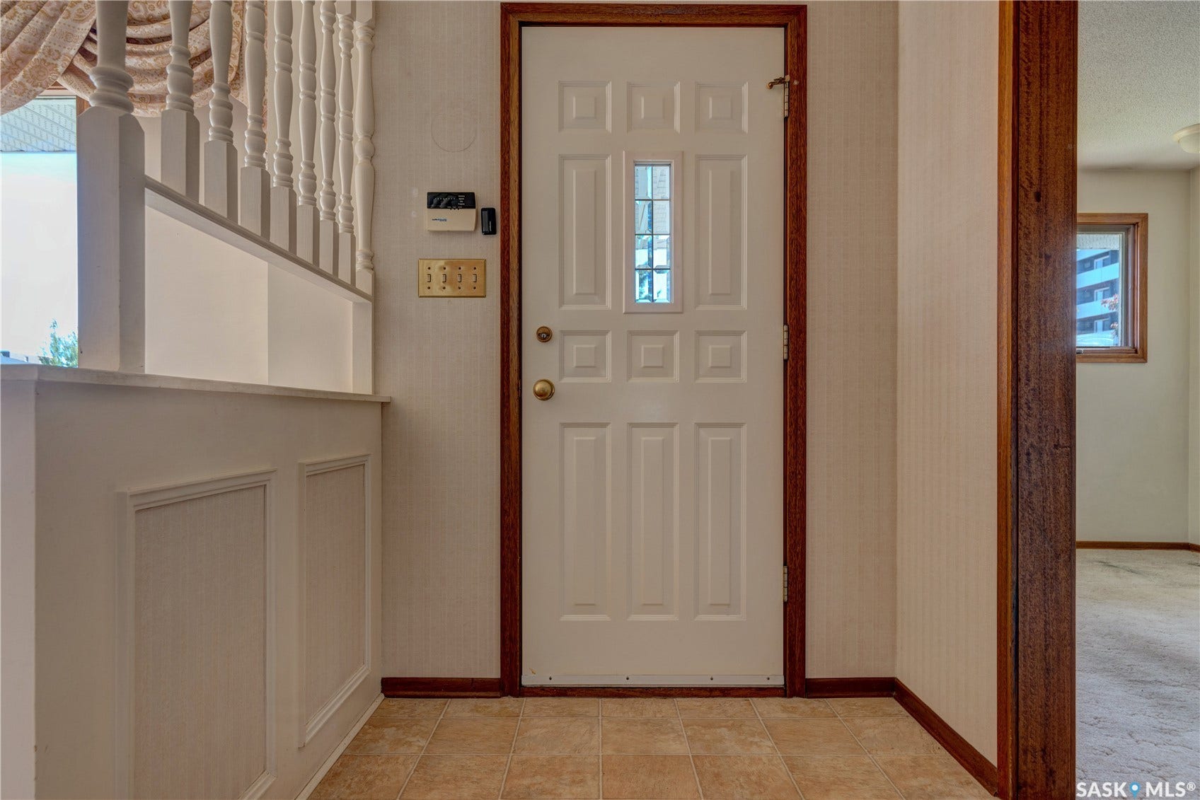 Paneled entry door with frosted glass insert, wood-finish trim, and ceramic tile flooring
