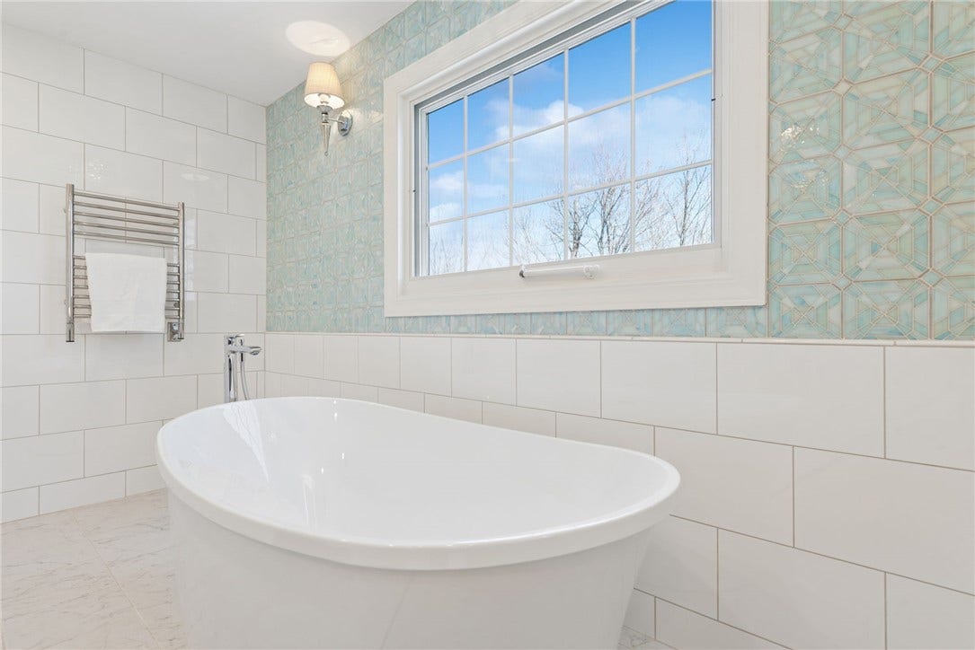 deep freestanding soaking tub with handcrafted watercolor mosaic wall tile & heated towel holders