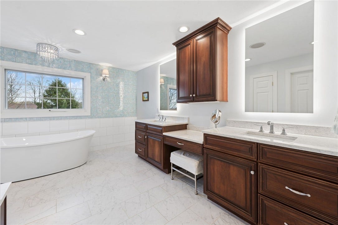primary luxury bathroom with double vanity and sinks with a makeup area. LED backlit mirrors