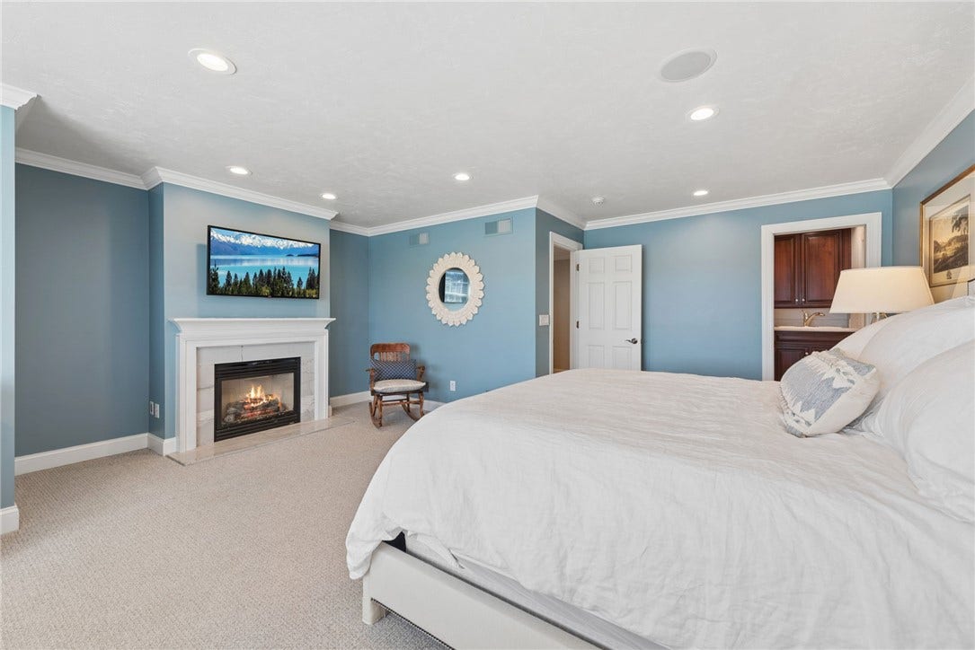 generously sized primary bedroom with gas fireplace, crown molding a seating area and lots of natural lighting come from the 4 windows overlooking the level back yard