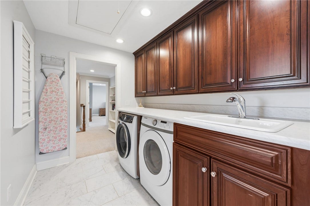 centrally located upstairs laundry room with a cast iron sink, additional cabinetry for storage and comfort height folding station