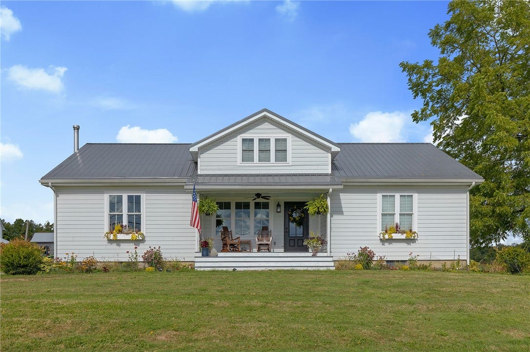 A classic farmhouse setting surrounded by barns, open fields, and peaceful country views