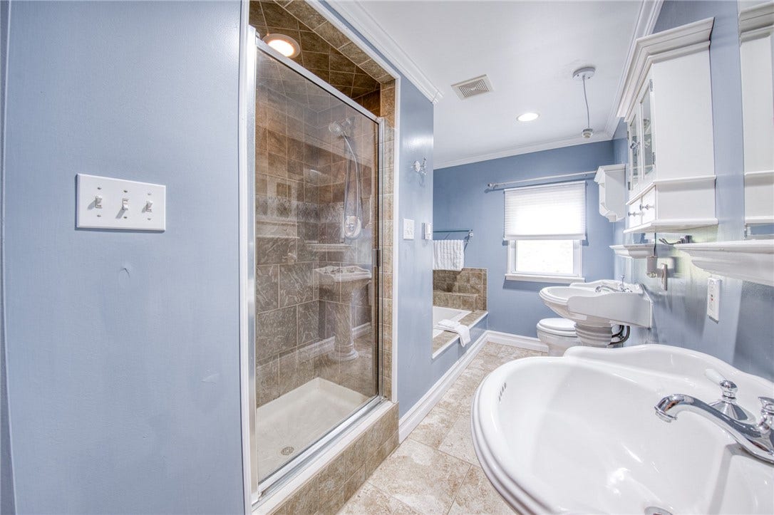 Bathroom with tub, shower, and dual sinks