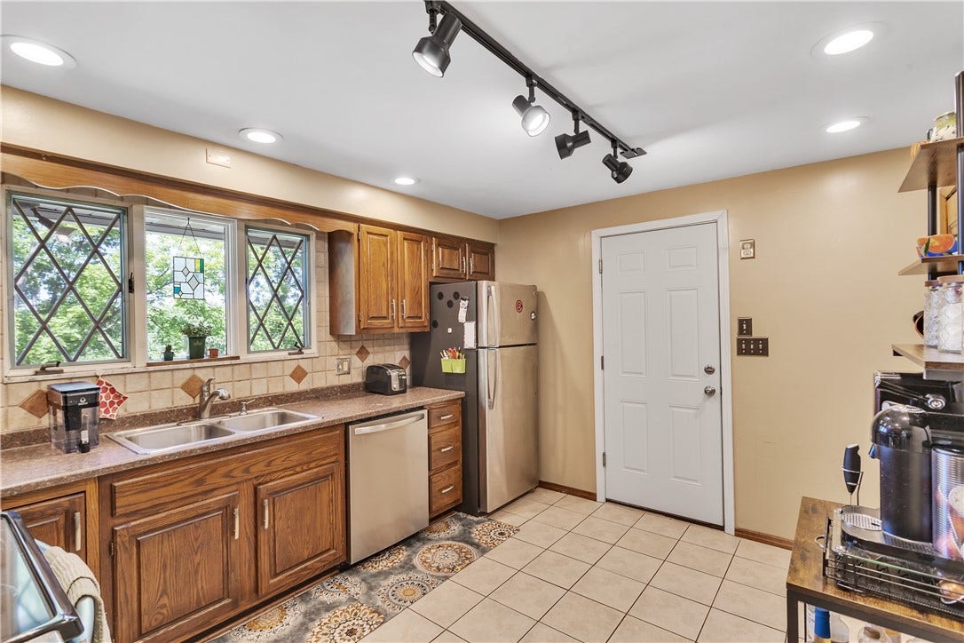 Neutral Laminate Tops, Oak Cabinets, Tile Backsplash, Stainless Appliances, and Tile Floor.
