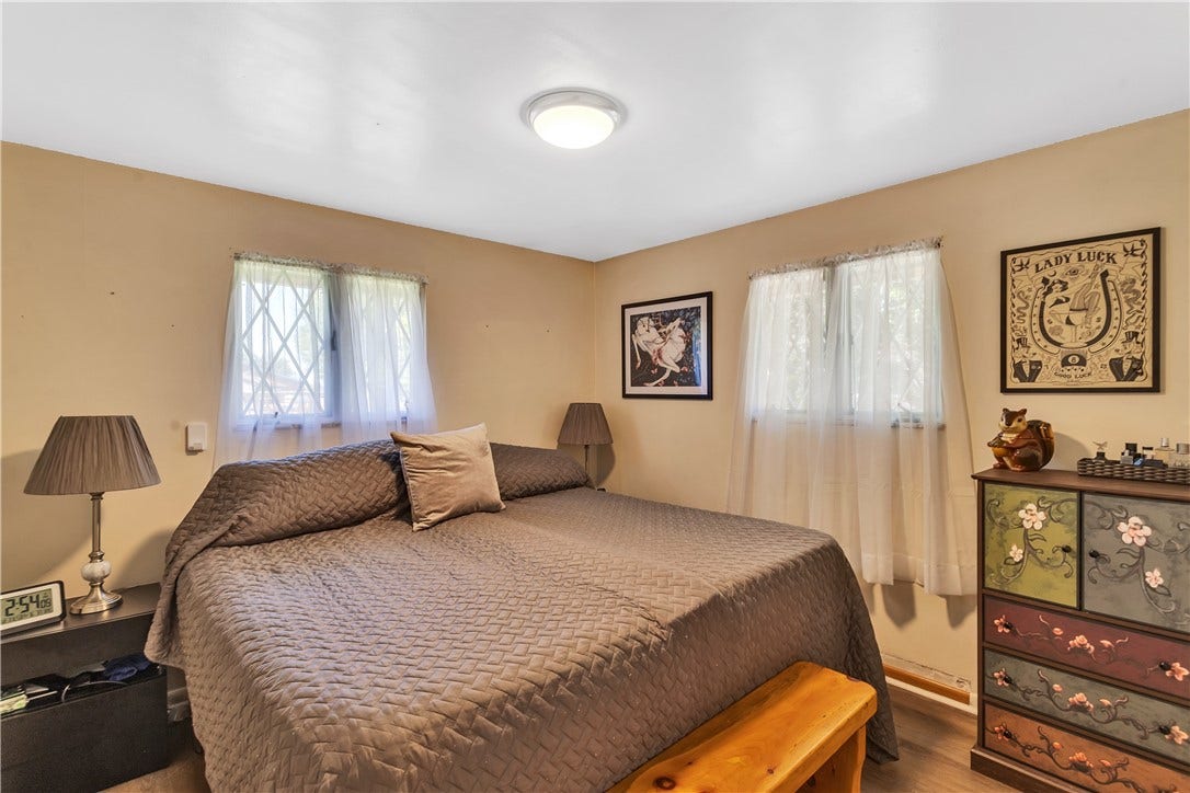 Bedroom #2 with Wood-Look Laminate Flooring, Neutral Paint, Lighted Closet, and 2 Sets of Windows.