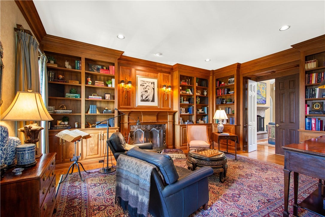 Stunning Library with a custom-built ins and black walnut paneling, shelving and wainscoting built on site with marbled faced gas fireplace.