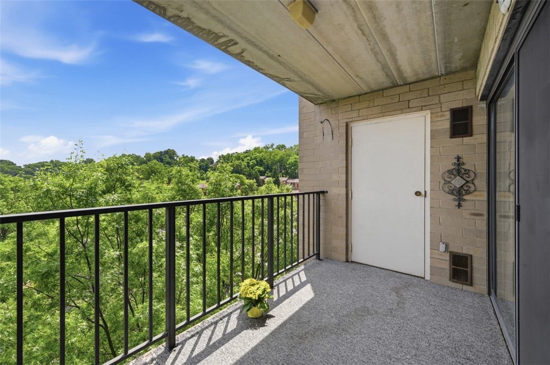 1400 Smokey Wood Dr, #601, Pittsburgh, PA 15218 Enjoy the spacious balcony overlooking Braddock Township, offering beautiful views of the surrounding landscape and the expansive blue sky.