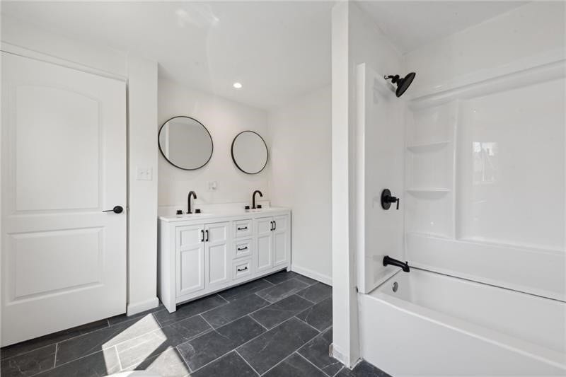 Main level full bathroom featuring double sinks.