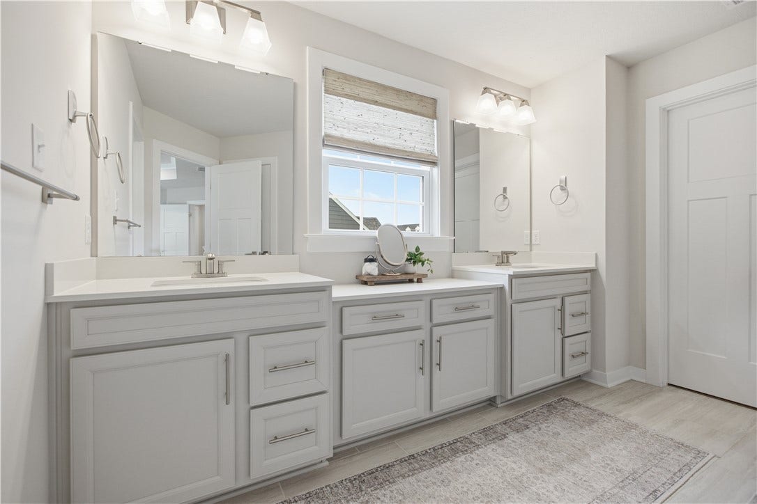 Spa-inspired bath features dual vanities, abundant cabinetry, expansive counters, and abundant natural light.