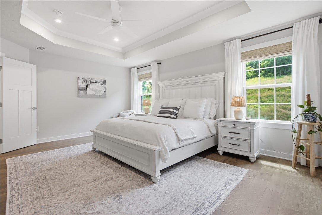 Elegant owner's suite with tray ceiling, oversized windows, abundant natural light, and spacious layout.